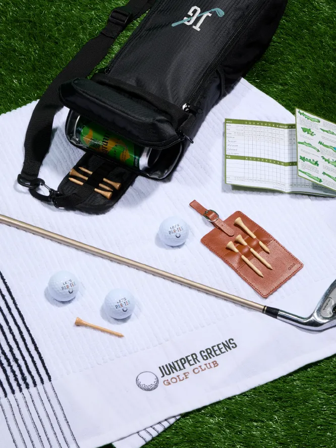 embroidered blanket on the ground with a custom golf bag, golf ball, tees, and tee holder