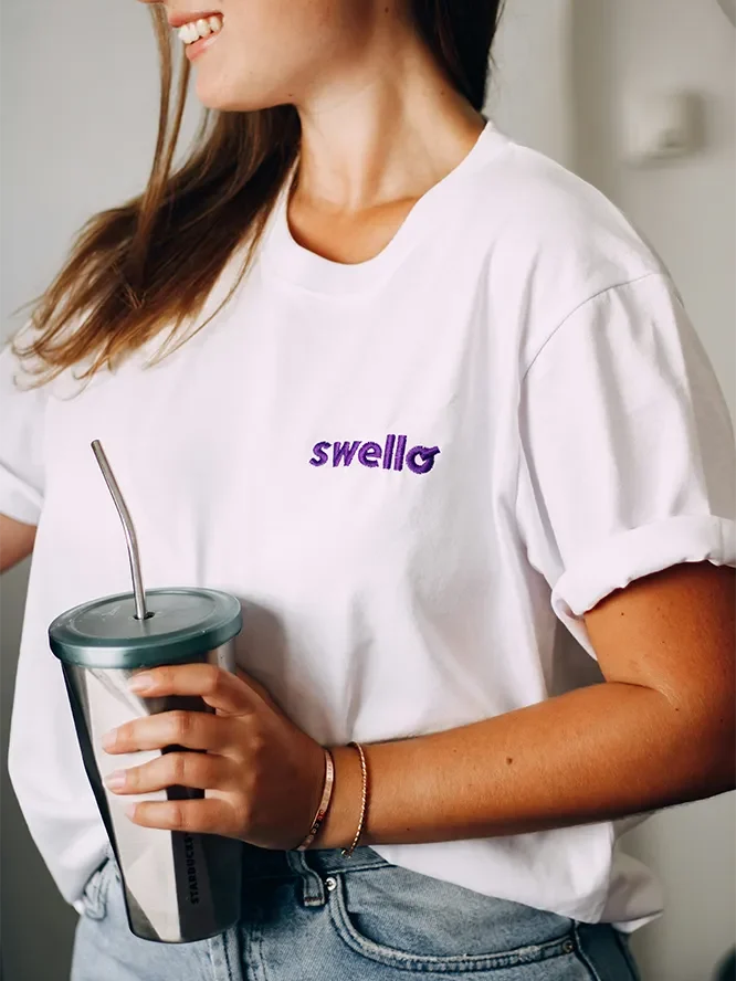 woman wearing a custom embroidered shirt and holding a water bottle